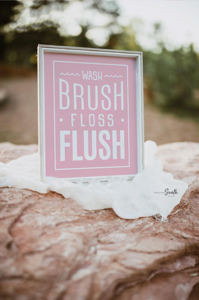 Pink bathroom wall art for girls featuring the phrases &quot;wash, brush, floss, flush&quot; in soft pink and white tones. Perfect for a girl&#39;s bathroom or powder room, this print adds a fun and feminine touch while encouraging daily hygiene routines. Ideal for children&#39;s bathroom decor, pink bathroom themes, or playful girly wall accents.
