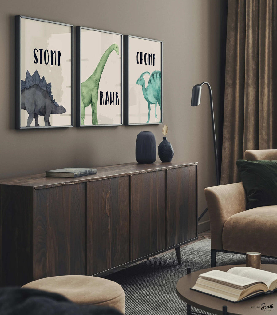 Watercolor dinosaur wall art set of 3 featuring a brachiosaurus, stegosaurus, and parasaurolophus in navy blue, green, and teal tones. Each print includes fun dinosaur-themed words: “Stomp,” “Roar,” and “Chomp,” making it perfect for a kids’ bedroom, playroom, or dinosaur-themed nursery. This playful and colorful artwork set adds a whimsical, prehistoric touch to any child’s space and makes a great gift for dino-loving toddlers or new parents decorating a gender-neutral nursery.