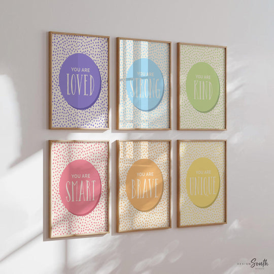 Set of 6 inspirational wall art prints for kids featuring rainbow-colored circles with modern speckled designs. Each print includes a positive affirmation: you are loved, you are kind, you are brave, you are smart, you are strong. Designed in purple, blue, green, pink, orange, and yellow for a vibrant and trendy playroom or nursery. This uplifting art set is perfect for encouraging confidence and positivity in babies, toddlers, or young children’s spaces.