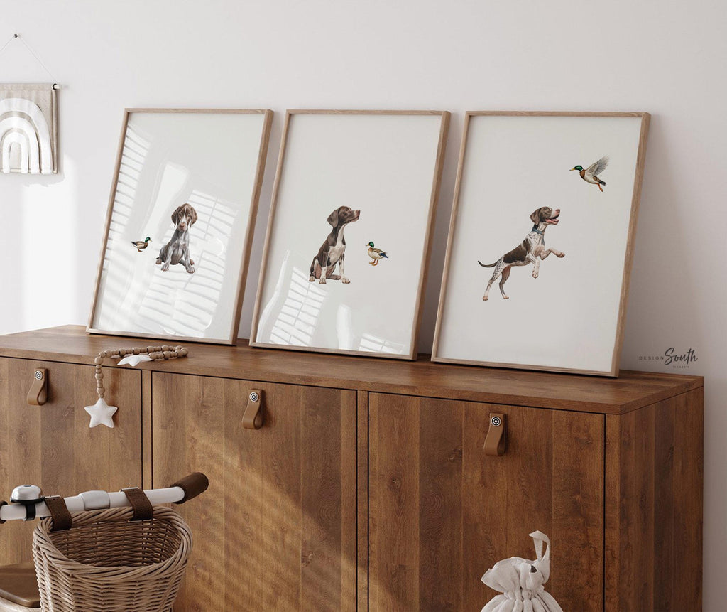 Set of 3 wall art prints featuring German Shorthaired Pointers (GSP) in a duck hunting scene, perfect for a toddler boy nursery or baby room. This series includes a pointing bird dog, a mallard duck taking flight, and a classic hunting dog stance. Designed for little boys who love the outdoors or come from hunting families, this bird dog artwork brings a rustic, adventurous feel to any space. Ideal for nurseries, playrooms, or as a unique gift for duck hunting enthusiasts.