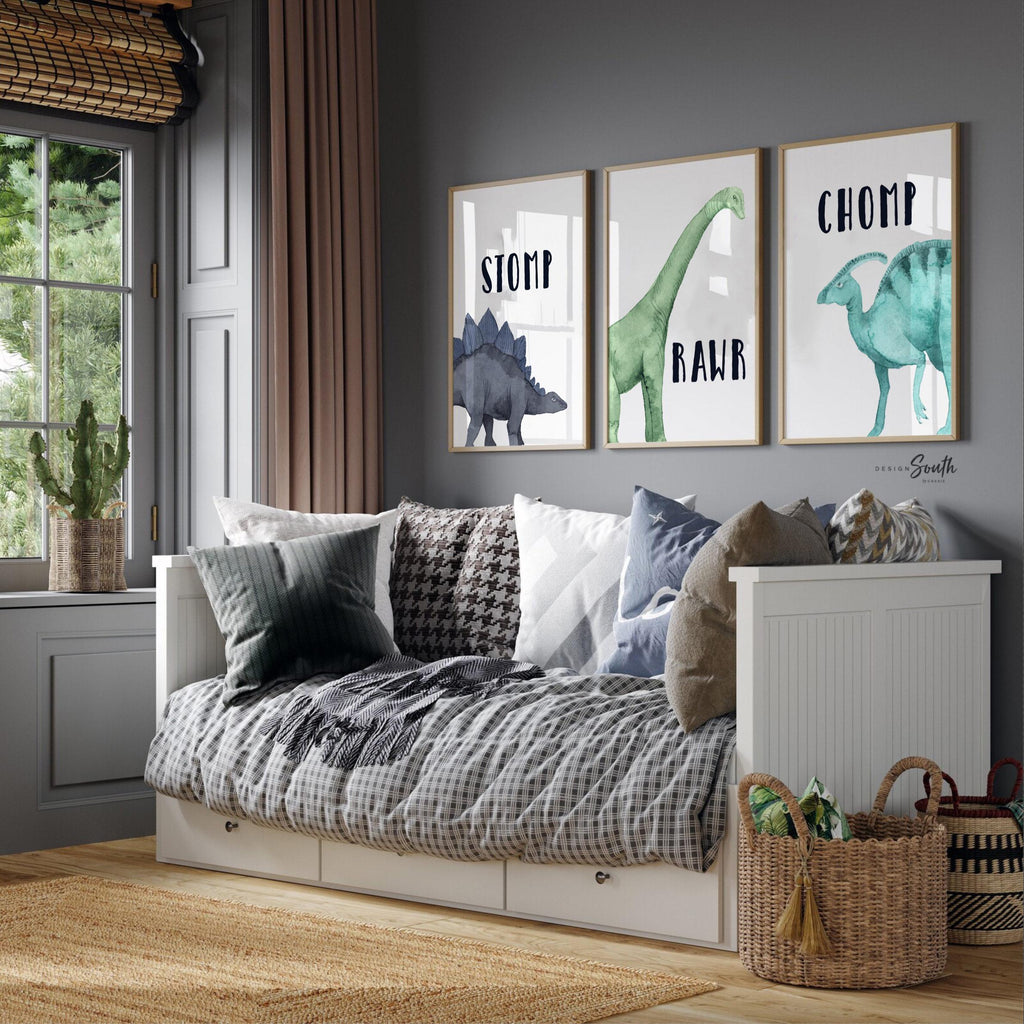 Watercolor dinosaur wall art set of 3 featuring a brachiosaurus, stegosaurus, and parasaurolophus in navy blue, green, and teal tones. Each print includes fun dinosaur-themed words: “Stomp,” “Roar,” and “Chomp,” making it perfect for a kids’ bedroom, playroom, or dinosaur-themed nursery. This playful and colorful artwork set adds a whimsical, prehistoric touch to any child’s space and makes a great gift for dino-loving toddlers or new parents decorating a gender-neutral nursery.